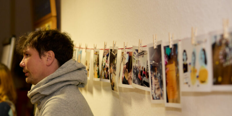 Fotos an einer Wäscheleine an der Wand . Links ein Mann, der gebannt der Musik lauscht.